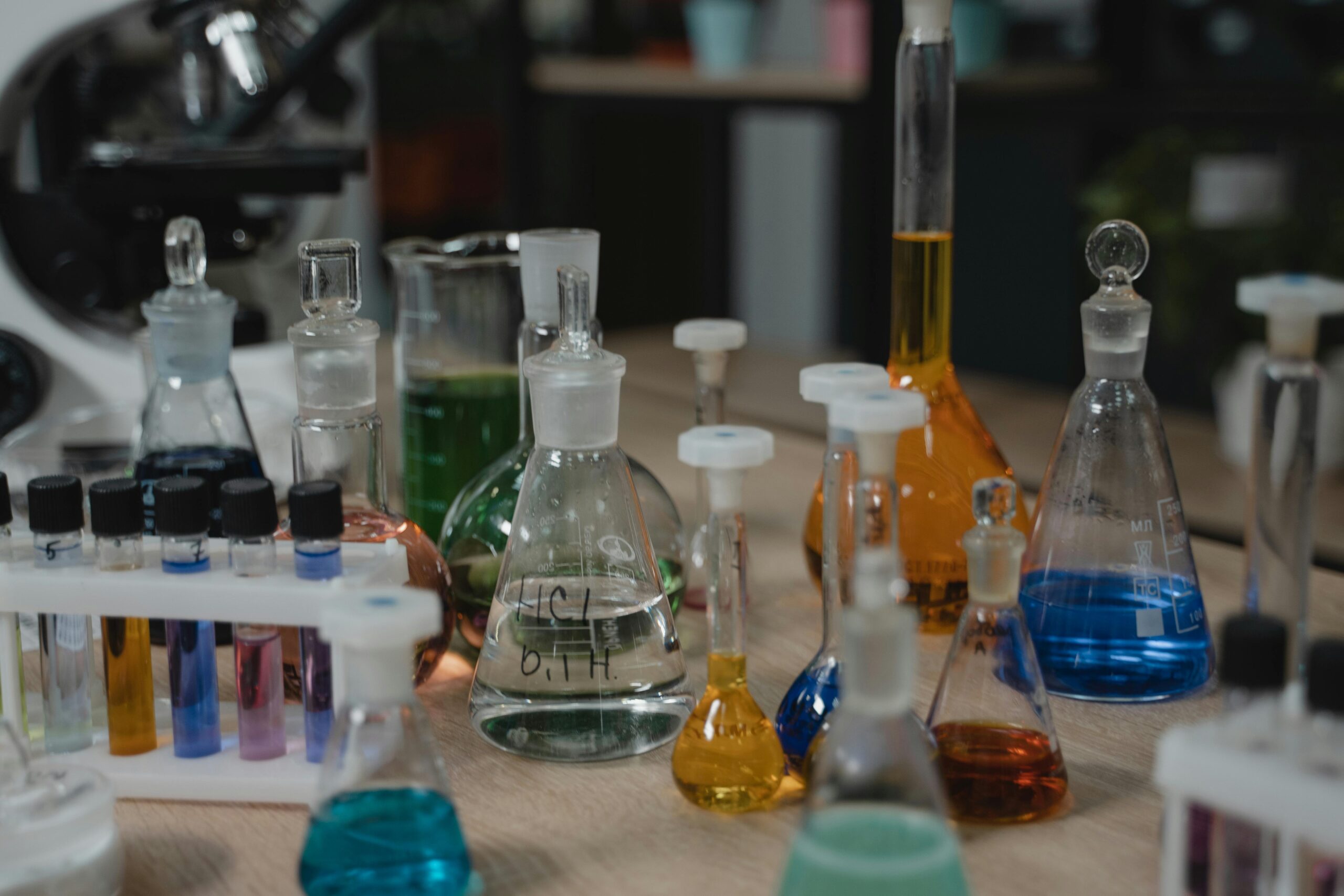 Various colored chemical liquids in glassware on laboratory table, perfect for scientific visuals.